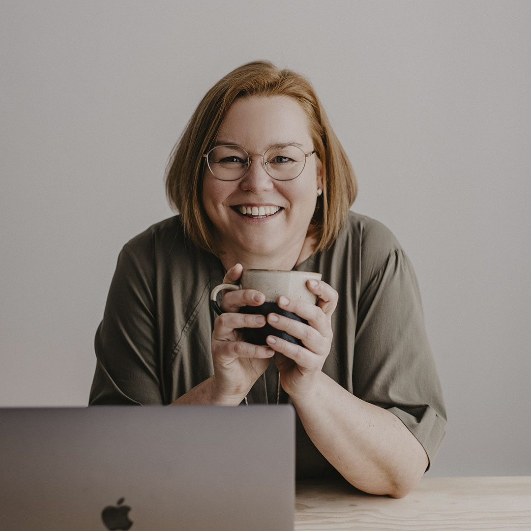 Agile Business Coach Melanie Stenger blickt von ihrem Arbeitsplatz aus in die Kamera